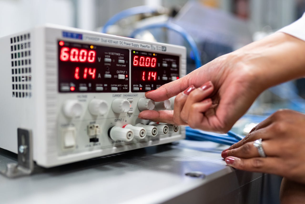 Services Close-up of a woman adjusting a DC power supply in a lab setting, indicating a hands-on approach to scientific research.